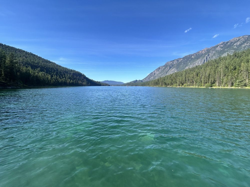 Clear blue lake between forested mountain slopes